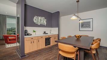 A modern kitchen with wooden cabinets, a dining table with chairs, and a pendant light.