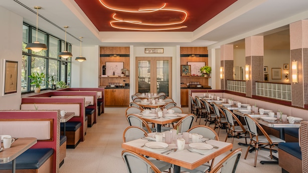 A restaurant with booths and tables, wooden paneling, and a neon light design on the ceiling. - Origin Baton Rouge, a Wyndham Hotel (Baton Rouge)