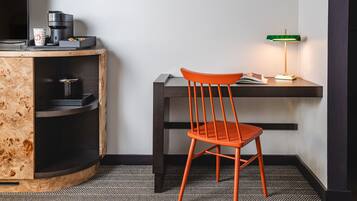 Un petit espace de travail comprenant un meuble en bois, une chaise, un bureau, une machine à café et une lampe de bureau verte.