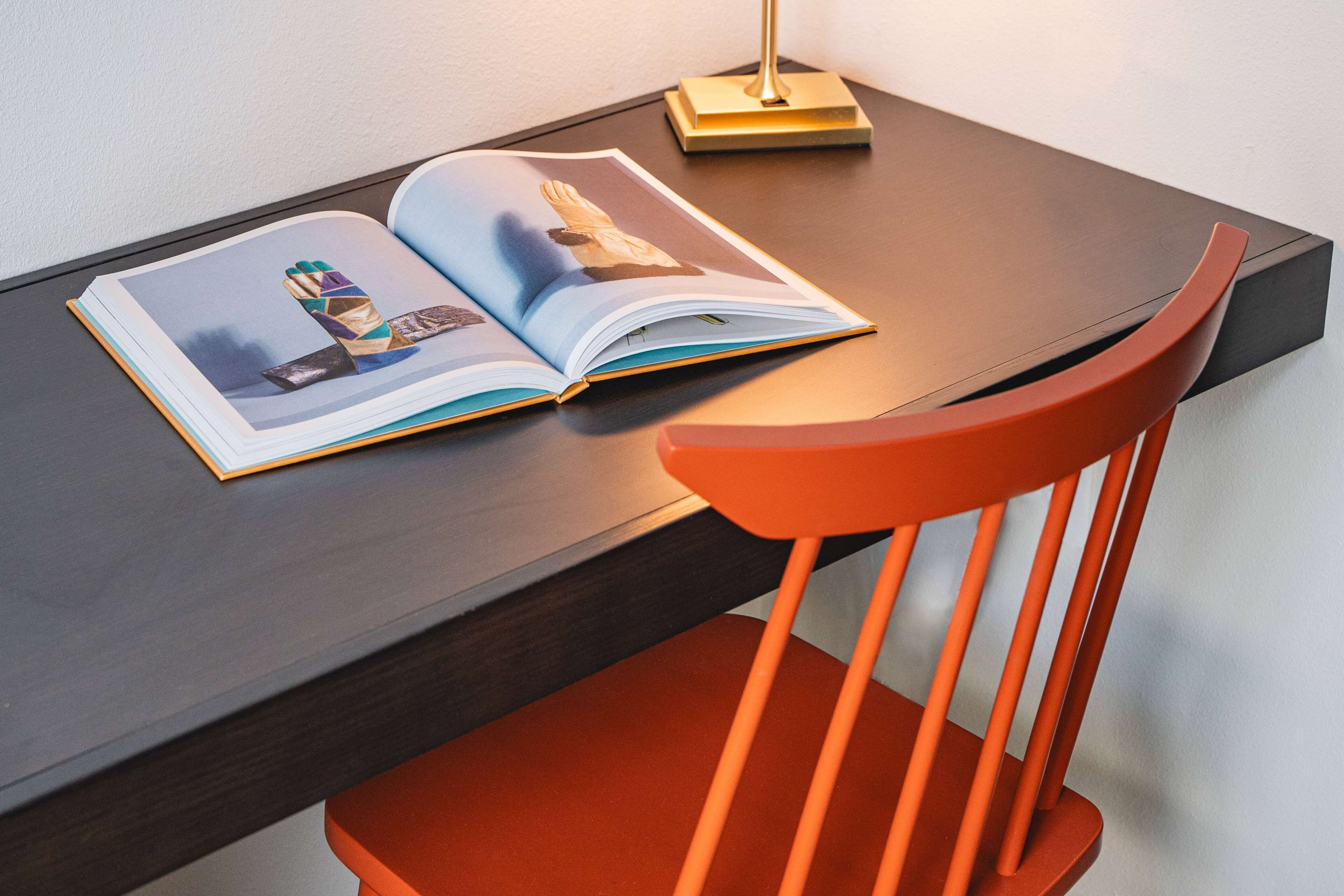 Un livre posé sur une table en bois foncé, avec une chaise rouge devant.