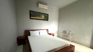 Un dormitorio con una cama de madera, una mesita de noche, una silla metálica y un cuadro en la pared.