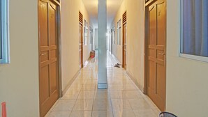 Un largo y estrecho pasillo con puertas de madera a ambos lados, que conduce a habitaciones individuales.