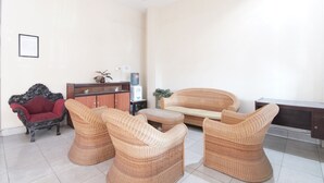 Una sala de estar con un sofá, dos sillones, un sillón rojo, un aparador y una mesita.