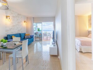 A modern hotel room with a balcony, a dining area, and a TV.
