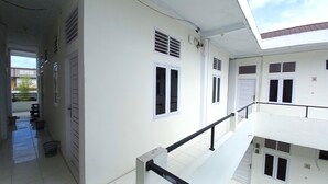 A multi-level building with white exterior walls, multiple windows, and a balcony with a black railing. - Hotel O Pondok Anie SyariahNearJembatan Siak (Pekanbaru)