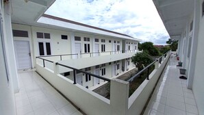 A multi-story building with balconies, white exterior walls, and a tiled floor. - Hotel O Pondok Anie SyariahNearJembatan Siak (Pekanbaru)