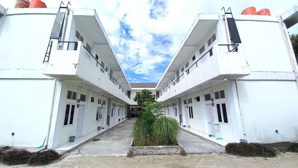 A symmetrical building with a central courtyard, featuring a row of rooms on either side, a central pathway, and a small garden area. - Hotel O Pondok Anie SyariahNearJembatan Siak (Pekanbaru)
