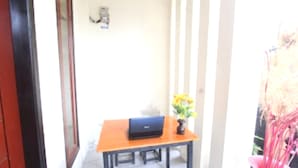 A room with a wooden table, a laptop, and a vase with flowers. - Hotel O Pondok Anie SyariahNearJembatan Siak (Pekanbaru)