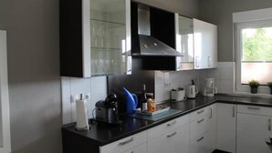 Una cocina moderna con armarios blancos, encimera negra y campana extractora de acero inoxidable.