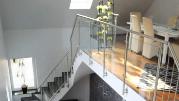 A spacious loft apartment with a mezzanine level, a staircase, and a large window providing natural light. - Schöne Eigentumswohnung mit Terrasse für 2 Pers (Bippen)