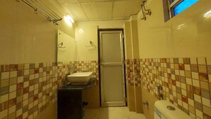 Ein Badezimmer mit gefliesten Wänden, einem Waschbecken, einer Toilette und einem Spiegel.