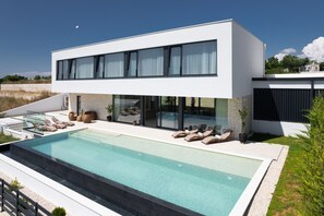 A modern two-story house with a large rectangular swimming pool, outdoor seating, and a clear view of the sky. - Villa Aurum ZadarVillas (Zadar)