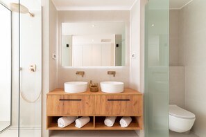 Un baño moderno con dos lavamanos, un espejo grande y cabina de ducha de vidrio.