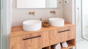 Une salle de bain moderne avec deux lavabos, un grand miroir et des meubles en bois.