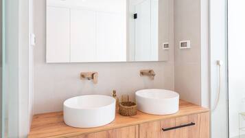 A modern bathroom with two sinks, a large mirror, and wooden cabinetry.