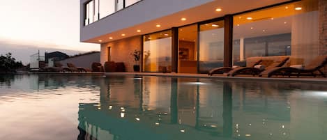 A modern house with a swimming pool, large windows, and outdoor seating.