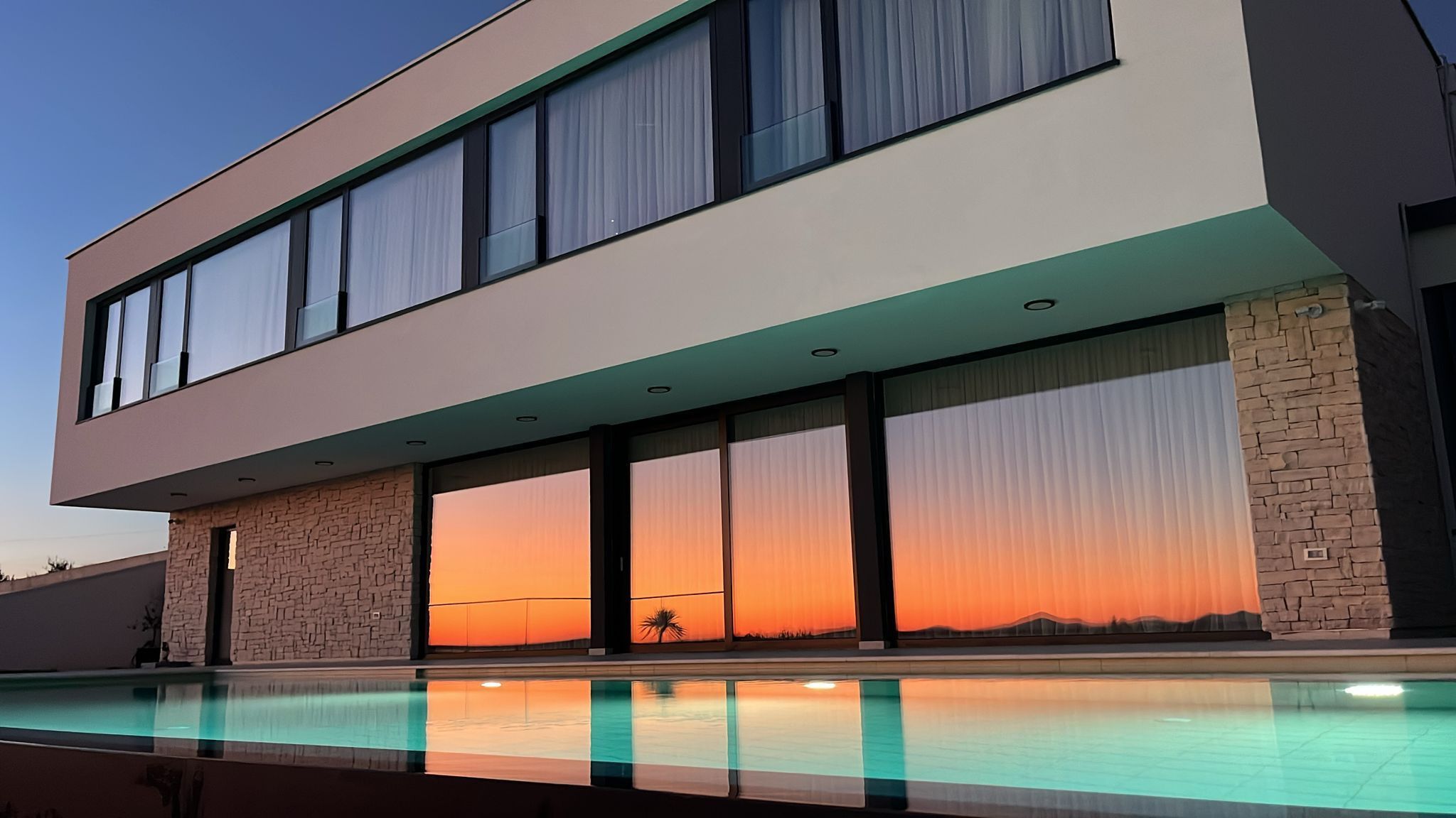 A modern two-story building with a swimming pool in front.