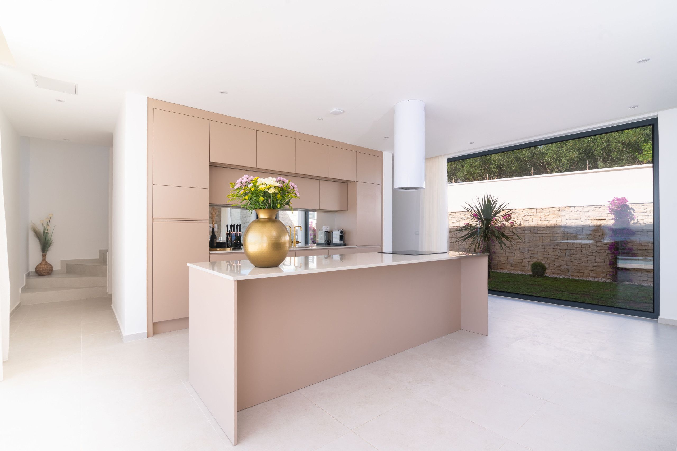 A modern kitchen with a central island, built-in appliances, and a large window offering a view of the outdoors.