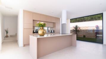 A modern kitchen with a central island, built-in appliances, and a large window offering a view of the outdoors.