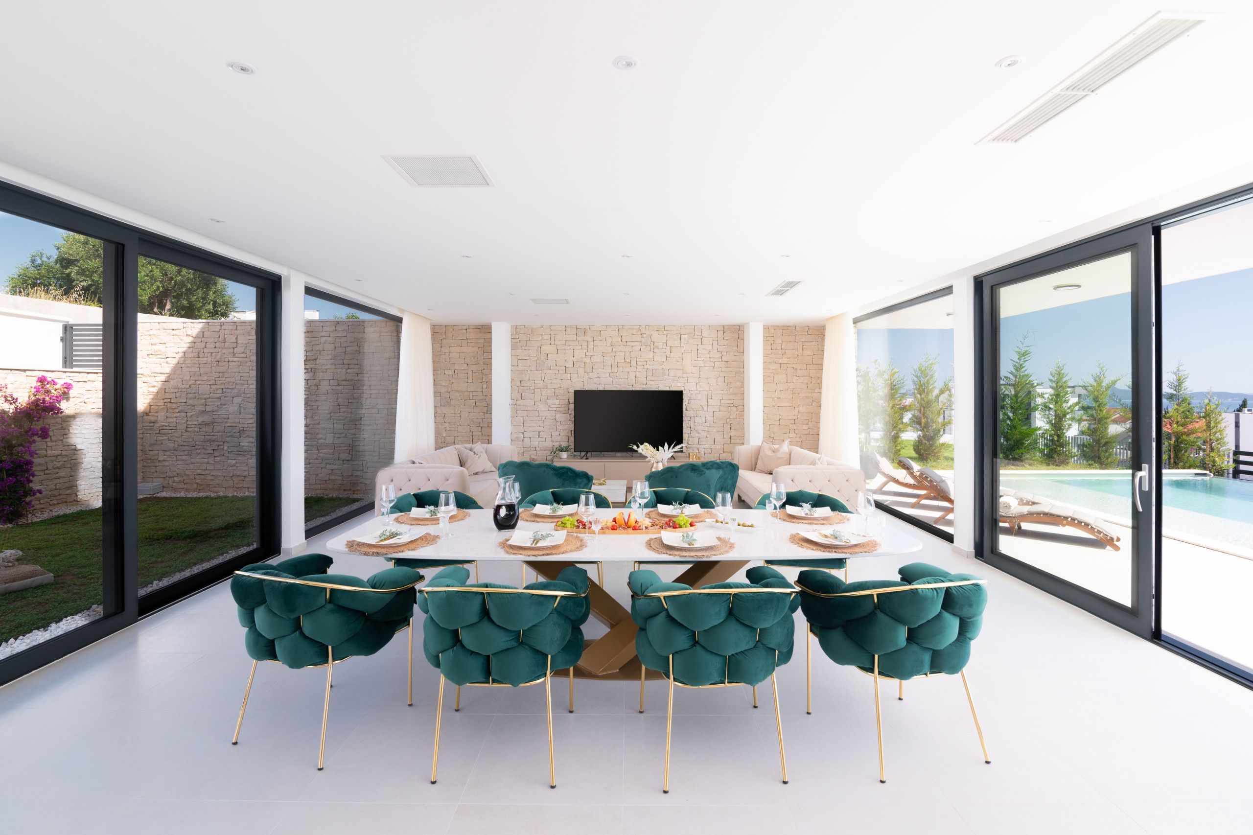 Un espace repas moderne avec une grande table, des chaises de couleur turquoise et un téléviseur fixé au mur.