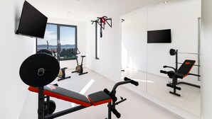 Une salle de sport moderne dotée d’une grande fenêtre, d’appareils d’exercice et d’un téléviseur fixé au mur.