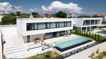 A modern two-story house with a swimming pool, outdoor seating, and a well-maintained garden.