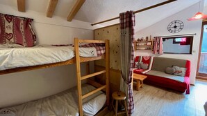 A cozy room with bunk beds, a sofa, a small table, and a clock on the wall.