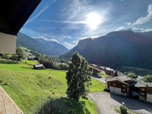 Paisaje montañoso con cielo despejado, algunos edificios y una carretera.