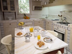 A well-lit kitchen with a marble countertop, a dining table set for breakfast, and a window with a view of trees. - Breathtaking views in a quiet part of Taormina, a stone's throw from downtown (Taormina)