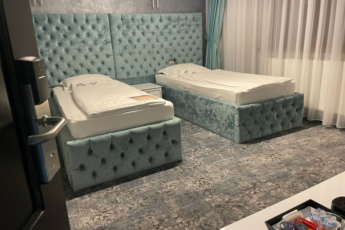 A hotel room with two beds, a minibar, and a small table with toiletries.