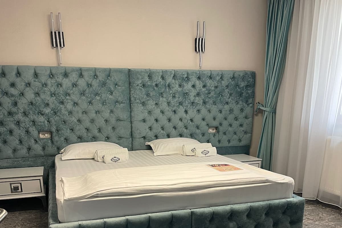 A bedroom with a large bed, a nightstand, and a dresser.