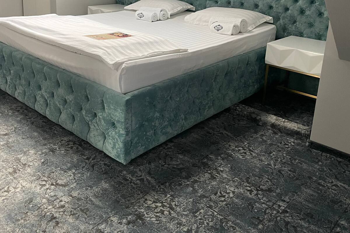 A modern bedroom with a large bed, a nightstand, and a wardrobe.