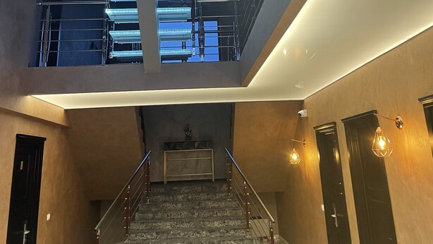 A modern interior with a staircase leading to a mezzanine level, featuring a skylight and a view of the sky. - Pensiunea Ramina (Adjud)