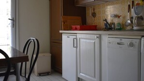 A compact kitchen with wooden cabinets, a white dishwasher, and a red plastic container on the counter.