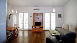 A living room with a wooden entertainment unit, a sofa, a coffee table, and a dining area with chairs. - Holiday house in Medulin, 150m from the beach (Medulin)