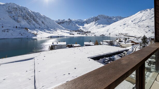 A snowy mountain landscape with a lake, buildings, and a wooden balcony. - Charming renovated apartment for 4 in Tignes with lake view (Tignes)