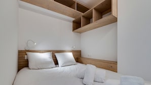 A bedroom with a wooden headboard, white bedding, and a built-in shelf above the bed. - Charming renovated apartment for 4 in Tignes with lake view (Tignes)