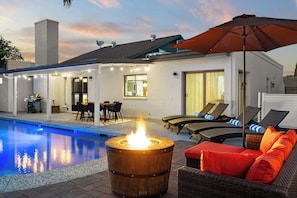 A poolside area with a fire pit, outdoor seating, and a covered patio.