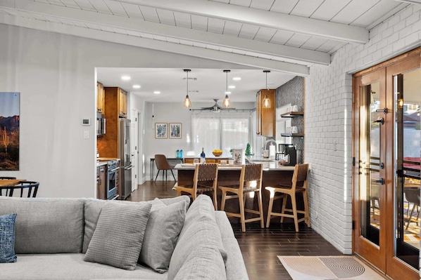 A modern kitchen with white brick walls, wooden cabinets, and a dining area with a table and chairs.