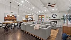A spacious living area with a large sectional sofa, dining table, and chairs, a kitchen in the background, and a fireplace. - Dobson Ranch, Farmhouse Casual, Pool & Games! (Mesa)