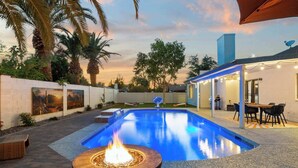 A swimming pool with a fire feature, a covered patio area, and a view of a building with satellite dishes. - Dobson Ranch, Farmhouse Casual, Pool & Games! (Mesa)