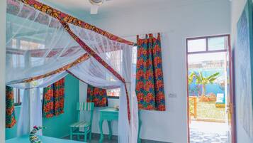 Habitación con cama bajo un dosel, un escritorio, una silla y una ventana con cortinas.