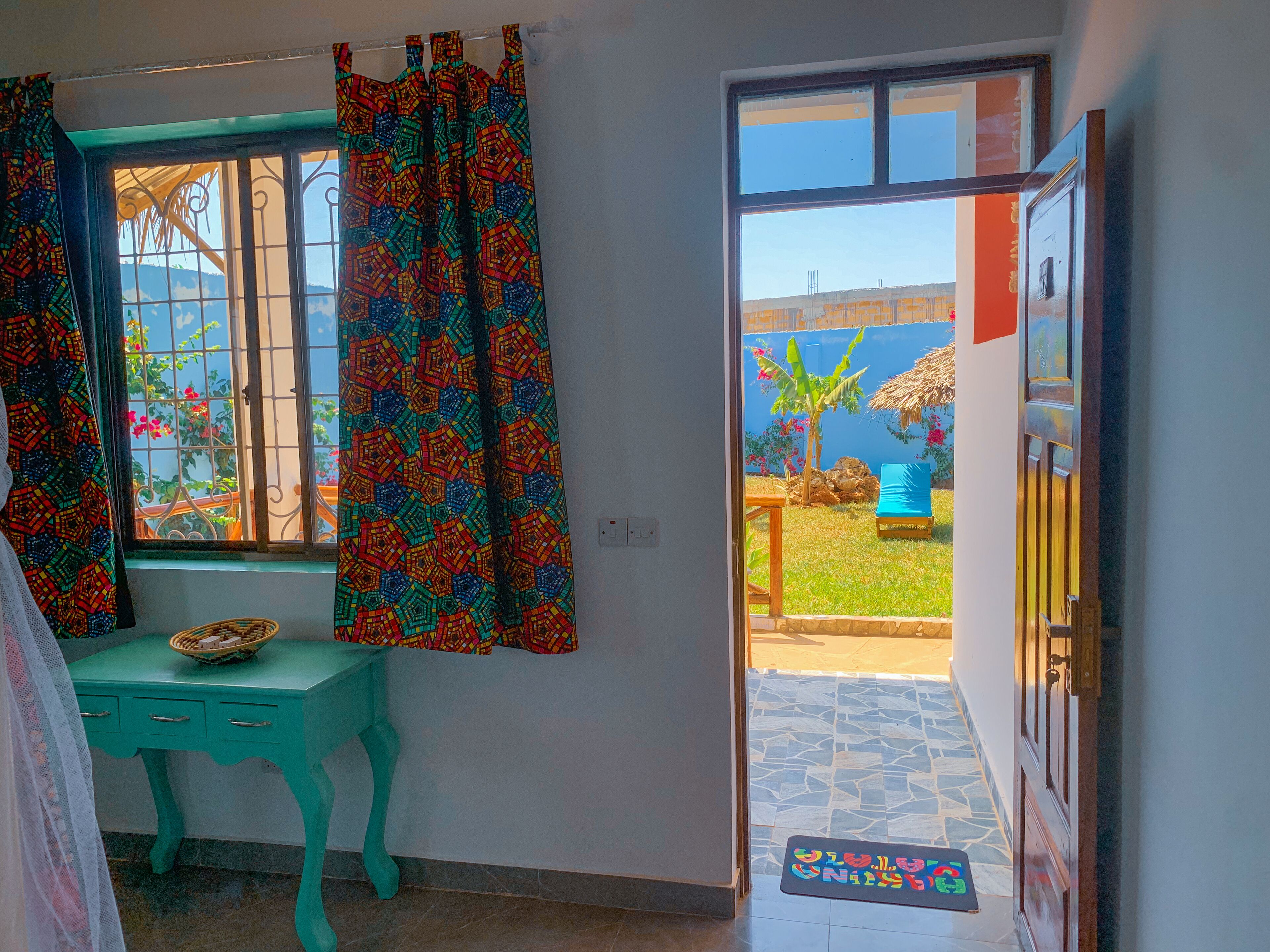 A room with a window, a teal desk, and a door leading outside.