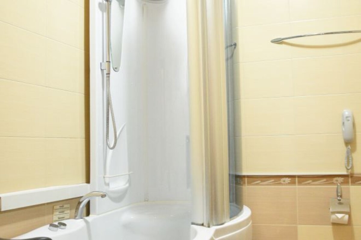 A shower area with a glass door, a handheld showerhead, and a wall-mounted telephone.