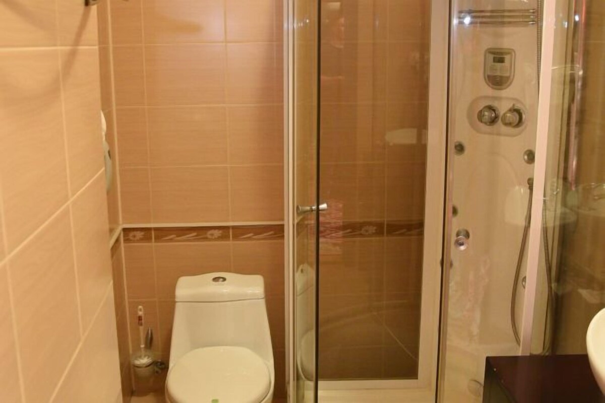 Un baño con inodoro, cabina de ducha con paredes de vidrio y lavamanos.