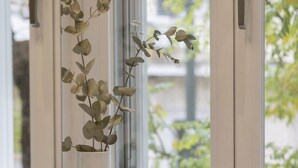 A bathroom with a white tiled backsplash, a white towel on the counter, and a vase with a plant on the windowsill. - Acropolis Maisonette 22 (Athina)