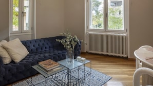 A modern living room with a blue sofa, a glass coffee table, and a patterned rug. - Acropolis Maisonette 22 (Athina)