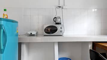 A kitchen with a microwave, a scale, and a blue refrigerator.