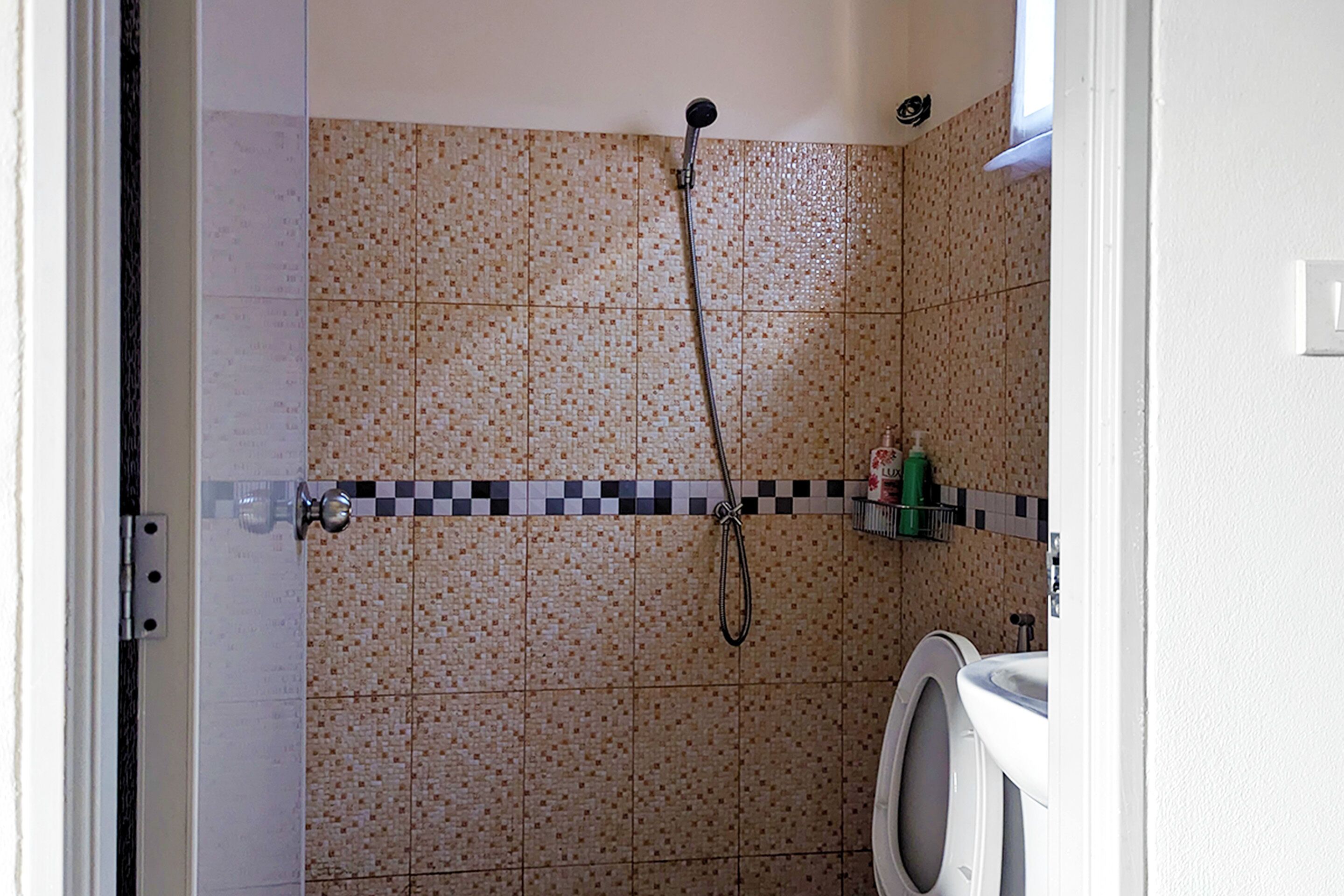 A bathroom with tiled walls, a shower, a toilet, and a sink.