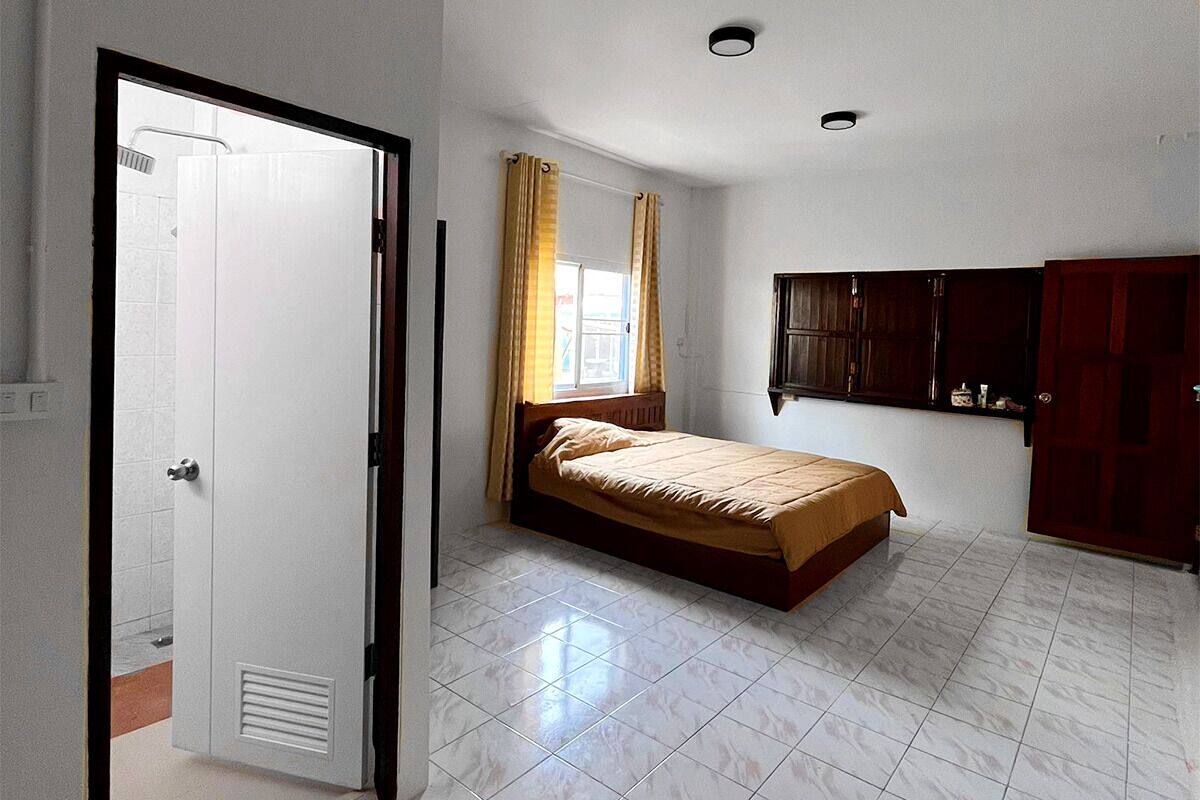 A bedroom with a bed, a window with curtains, a wardrobe, and a door.